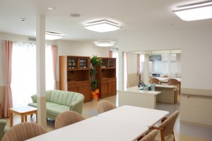 木製家具と観葉植物を配置した明るい共用リビングスペース